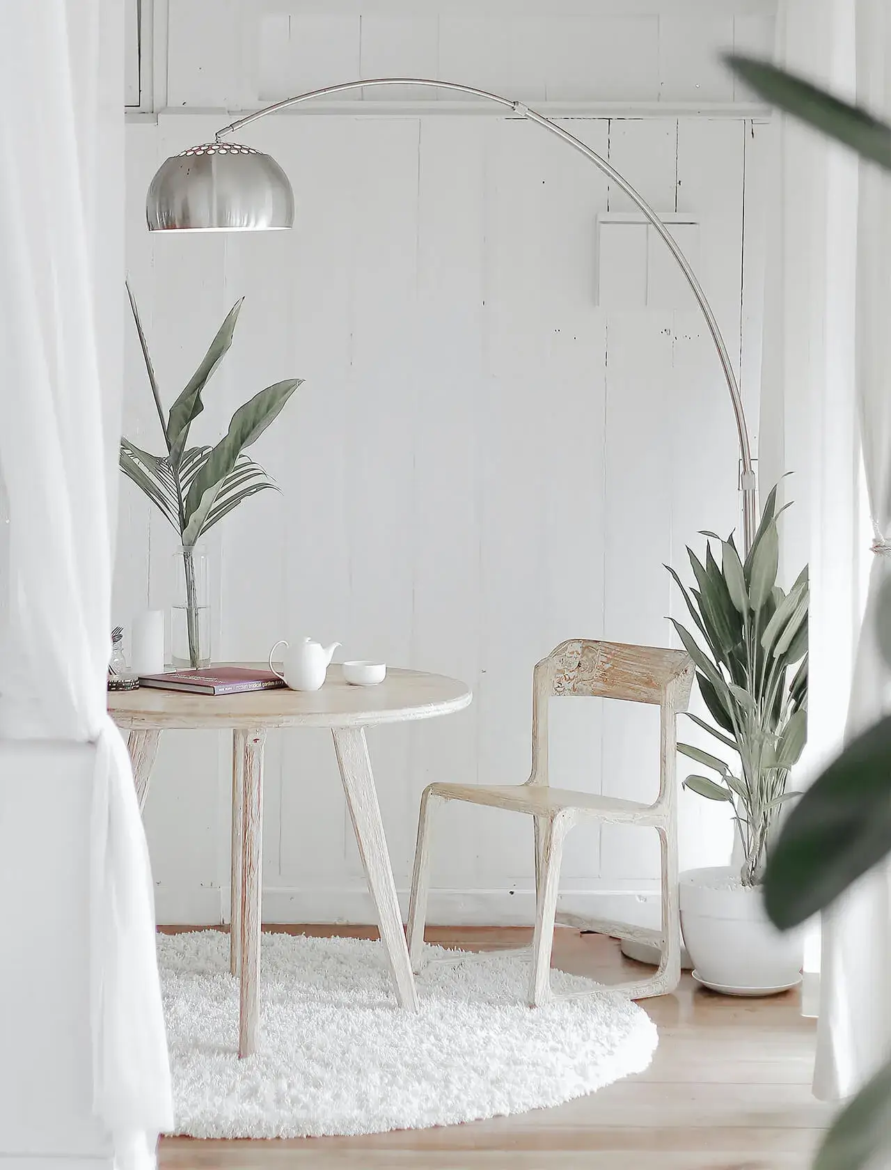 Helles, minimalistisches Esszimer mit Pflanzen und Bogenlampe.